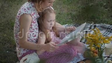 一对幸福<strong>的</strong>母女在相册里看照片读一本书。 一<strong>家</strong>人在城市公园野餐，在<strong>温暖的</strong>晚上。